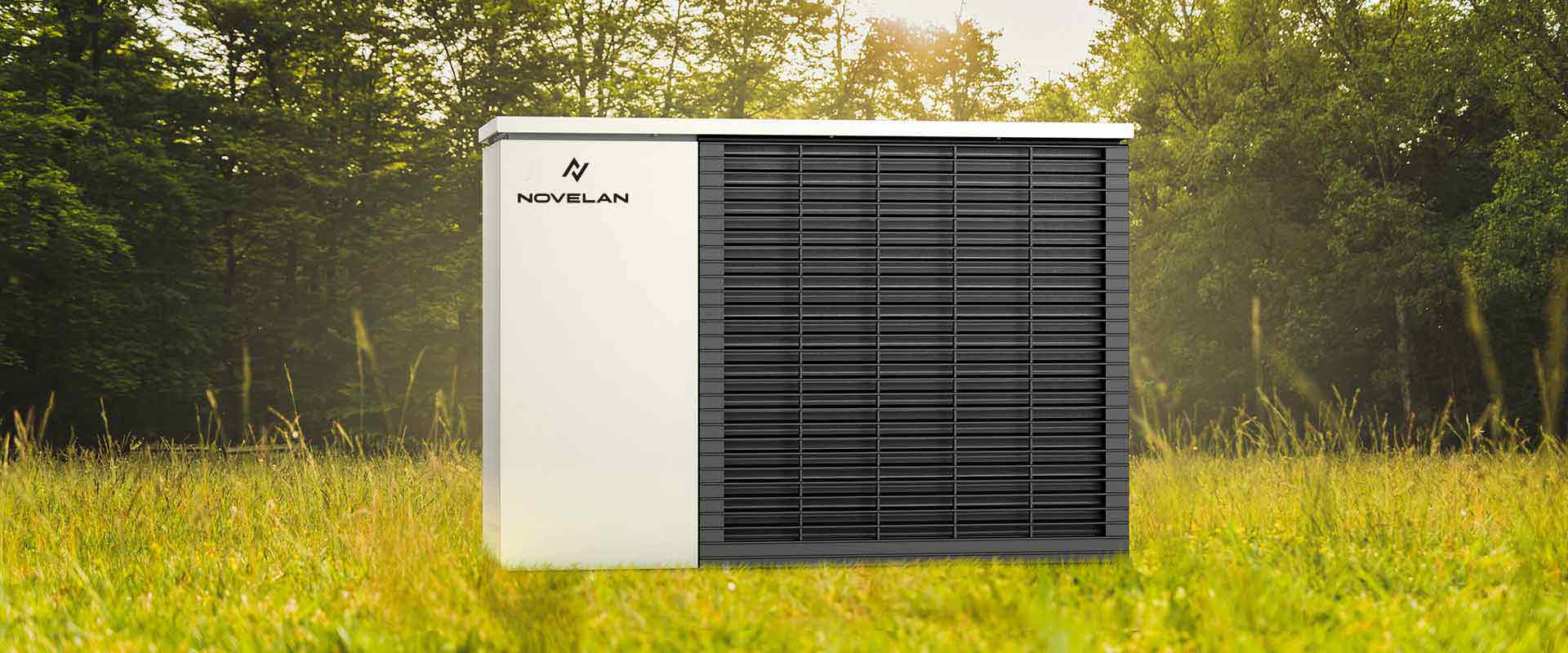 The air/water-heat pump LADV can be seen with a ventilation grille on the right front and the NOVELAN logo in the upper left corner as it stands on a pasture with a forest in the background.